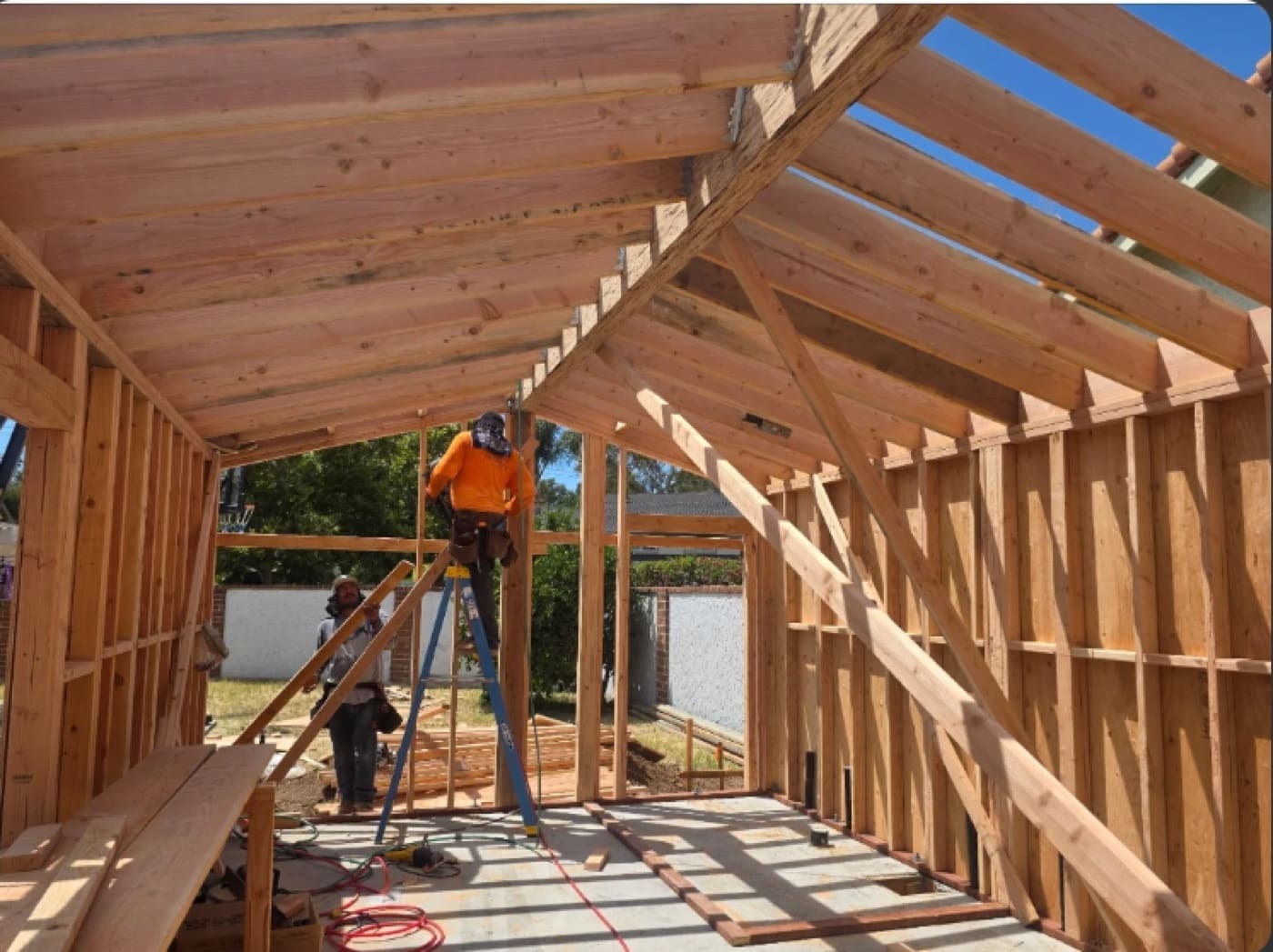 ADU wall and roof framing standing on the cured slab with crew installing rafters