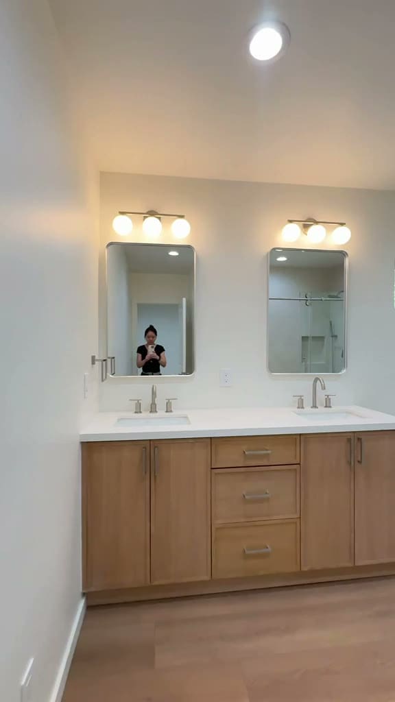 Double vanity with twin mirrors and globe sconces in a Pasadena ADU bathroom
