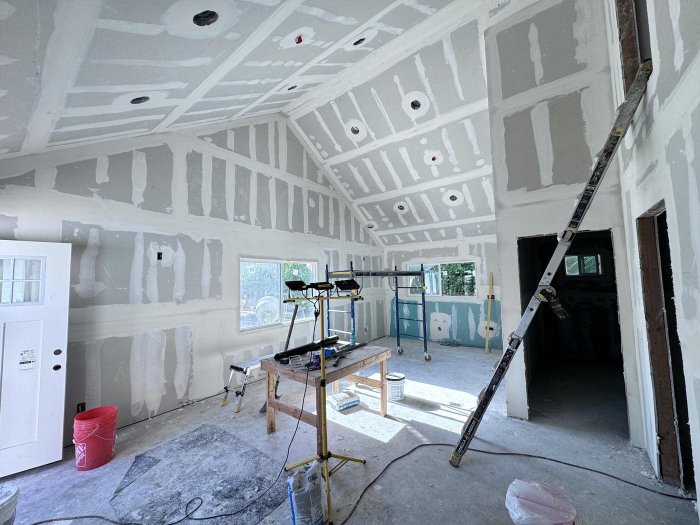 Drywall and taping stage inside a Pasadena ADU, showing the vaulted ceiling and recessed can lights