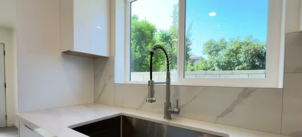 Quartz counter and stainless farmhouse sink under a garden window in a Rosemead ADU kitchen