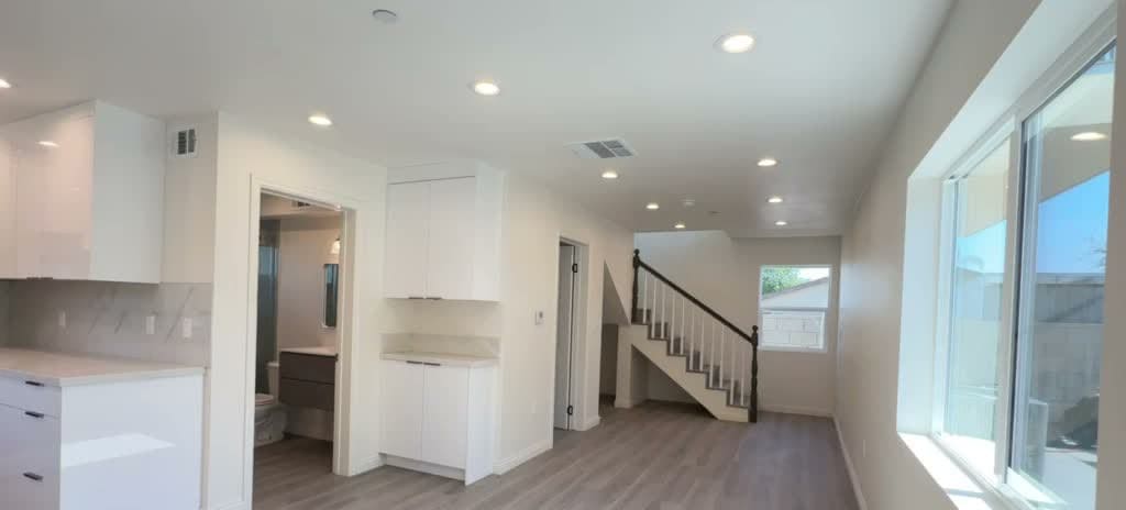 Open floor plan living and kitchen area of a two-story ADU in Rosemead with staircase and luxury vinyl plank flooring